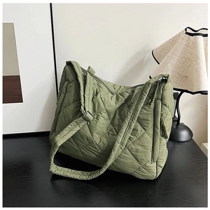 Detail view of army green quilted puffer tote bag on a black wooden surface