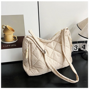 Macro detail of beige quilted puffer tote bag with side zipper and diamond stitch texture