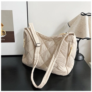 Detail of beige quilted tote bag with diamond stitching and adjustable shoulder strap