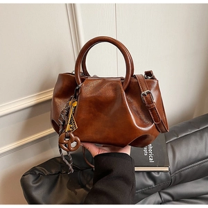Détail du sac seau marron vintage avec texture plissée et pendentif biscuit élégant