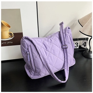 Detail of purple quilted crossbody bag with diamond patterns and adjustable strap