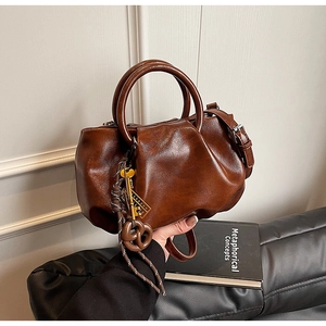 Détail d'un sac seau plissé vintage marron foncé avec charm bretzel et bandoulière
