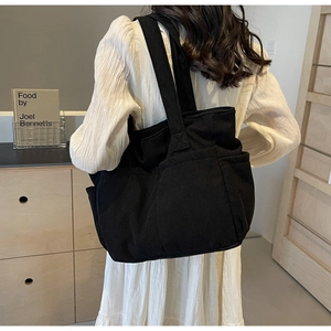 Vue arrière du grand sac cabas en velours côtelé noir porté par un mannequin chic