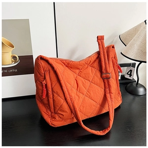 Detail of bright orange quilted tote bag with diamond lattice pattern and woven zipper