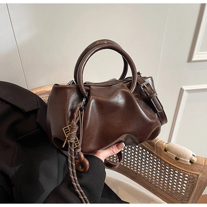 Détail du sac seau plissé en cuir marron foncé avec corde tressée et pendentif doré