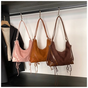 Detail view of vintage frosted tote bags in pink, caramel, and dark brown with lace-up accents