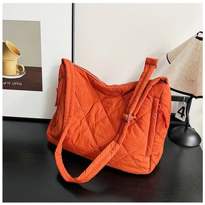Detailed view of the bright orange quilted tote bag with diamond stitching and strap