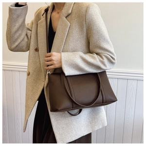Detailansicht der dunkelbraunen Leder-Einkaufstasche mit Litschi-Muster und beigem Blazer