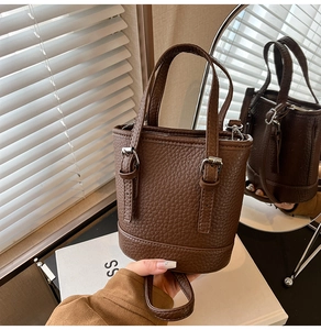 Close-up of brown litchi pattern leather bucket bag with metallic buckle detail