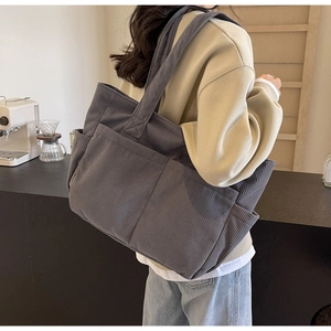 Détail du grand sac cabas en velours côtelé gris foncé avec des poches et texture côtelée
