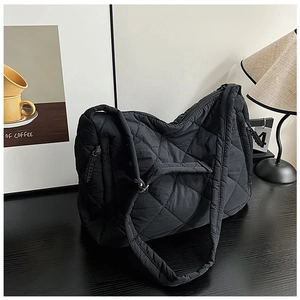Macro shot of black quilted nylon puffer tote bag with diamond lattice pattern and soft texture