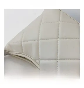 Detailed close-up of cream quilted pattern stitching on a minimalist shoulder bag