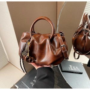 Détail du sac seau plissé marron foncé avec pendentif clé en métal rétro et bandoulière