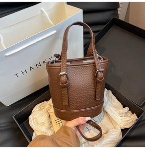 Close-up of brown litchi pattern bucket bag with silver buckle and crossbody strap