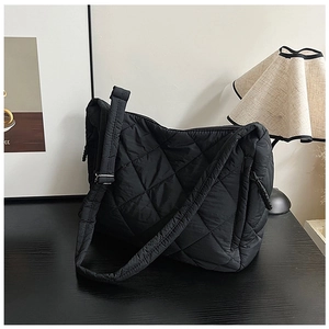 Macro detail of black quilted puffer bag with chic diamond stitching and wide strap