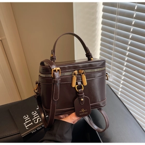 Detail of a dark brown leather vanity case bag with gold hardware and top handle
