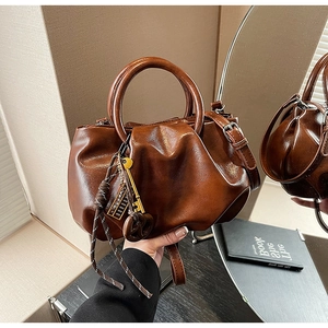 Détail du sac rétro marron plissé avec breloque clé dorée et détails en corde tressée