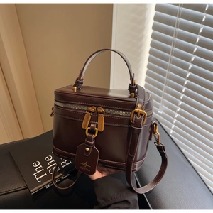 Detailed macro view of dark brown box bag with smooth finish and gold dual-zipper hardware