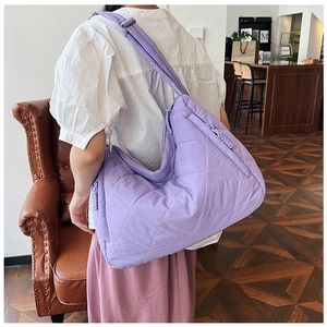 Detail of a lilac quilted tote bag with diamond stitching and adjustable nylon strap