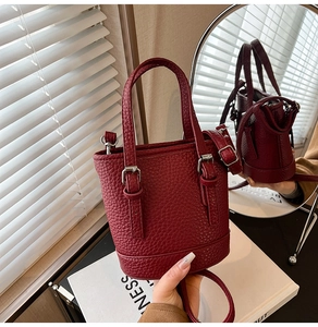 Macro shot of burgundy bucket bag featuring pebbled leather texture and silver buckle detail