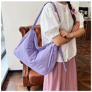 Close-up of lavender quilted nylon crescent bag featuring diamond stitching and wide strap