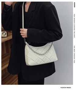 Detail of off-white quilted shoulder bag featuring silver chain and zip closure design