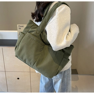 Détail d'un sac cabas en velours côtelé vert foncé avec poche latérale sur un mannequin