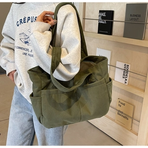 Détail du grand sac cabas en velours côtelé vert foncé avec poches extérieures et large bandoulière