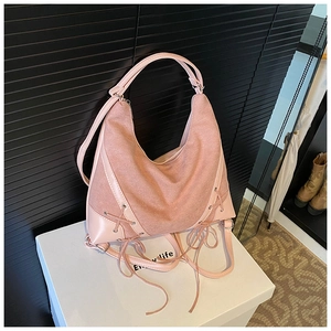 Detail of pink hobo bag featuring mixed leather textures and decorative side lacing