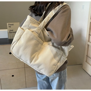 Détail du sac fourre-tout en velours côtelé écru montrant la texture et les poches latérales