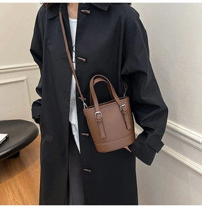 Close-up of textured dark brown leather bucket bag with metallic buckle details