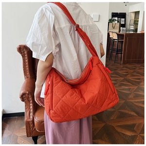 Close-up of orange quilted nylon tote bag featuring diamond pattern stitching on shoulder