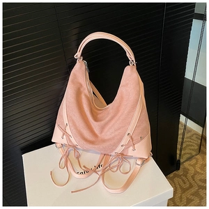Detail of pink faux suede shoulder bag featuring decorative fringe ties and top handle