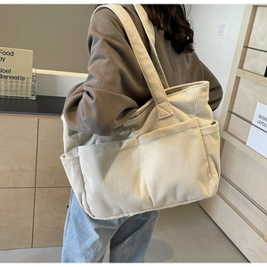Vue détaillée du sac cabas en velours côtelé crème montrant les poches et la texture