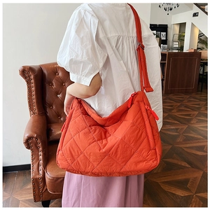 Detail of orange quilted tote bag featuring large diamond stitching and wide strap