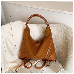 Detail of a brown frosted leather hobo bag with tied lace decor on a white suit