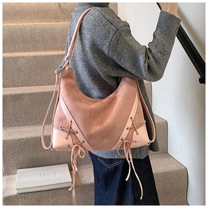 Close-up of pink hobo shoulder bag with matte finish and lace-up side details