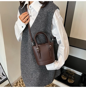 Detailed view of dark brown lychee pattern bucket bag styled as a crossbody on model