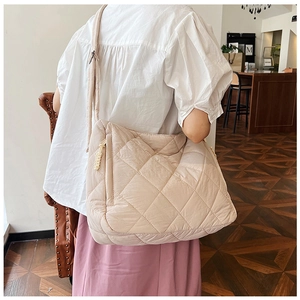 Close-up of beige quilted puffer tote bag featuring large diamond stitching and wide strap