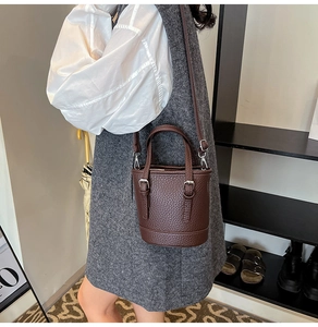 Detail of dark brown lychee pattern bucket bag with silver hardware and adjustable strap