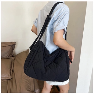 Detail of black quilted puffer tote bag showing diamond stitching and adjustable strap
