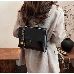 Detailansicht des schwarzen Lackleder-Rucksacks am Model mit Seidentuch und Glocke