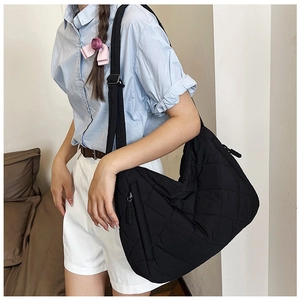 Detail of black quilted puffer tote bag showing zipper pocket and adjustable strap