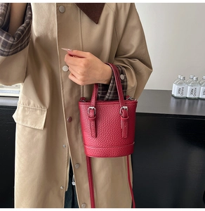 Macro shot of red pebble leather bucket bag with silver buckle and crossbody strap