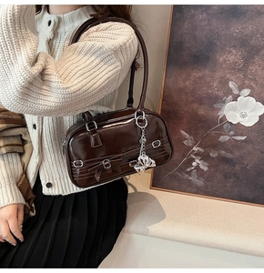 Détail du sac sous l'aisselle marron foncé brillant avec breloque papillon argentée