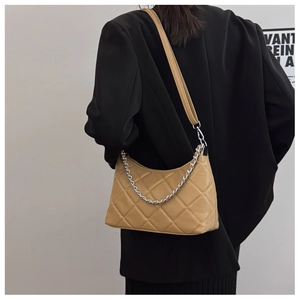 Detail of beige quilted shoulder bag with silver metal chain and leather strap