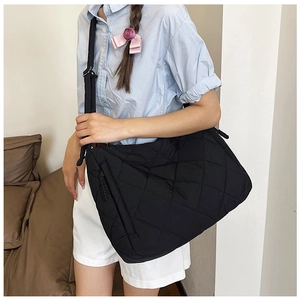 Detail of black quilted puffer crossbody bag showing side zipper pocket and adjustable strap