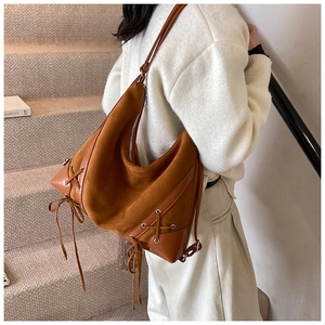 Detailed side view of vintage brown suede tote with unique cross lacing and metal zipper