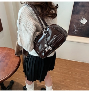 Détail du sac en cuir marron brillant avec boucle argentée et pendentif cœur noeud