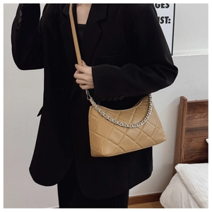 Detail of light brown quilted crossbody bag with stylish silver metal chain decoration